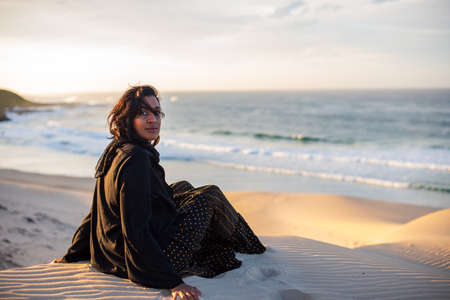 Woman sitting at the edge of sand duneの写真素材