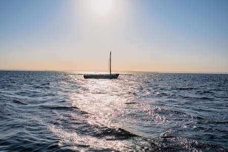 Dhow boat seen on water with people in distance