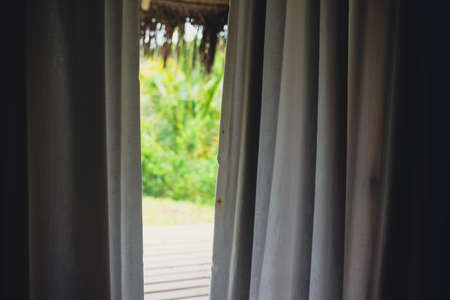 Slightly opened curtain with blurred background of natureの写真素材