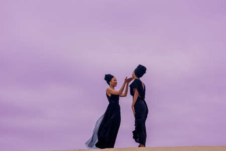 Two woman seen standing on top of sand duneの写真素材