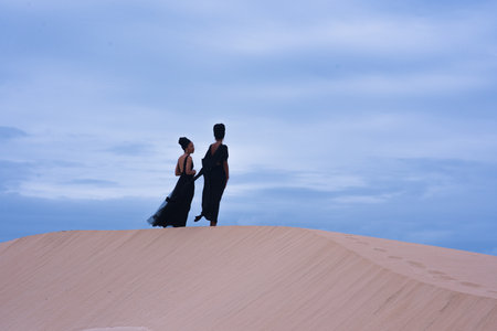 Landscape shot of two woman standing on sand duneの写真素材