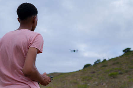 rear view of young man seen operating a droneの写真素材