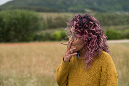 Portrait of woman standing and smoking a cannabis jointの写真素材