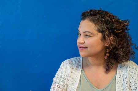 Portrait of winking woman shot against blue background