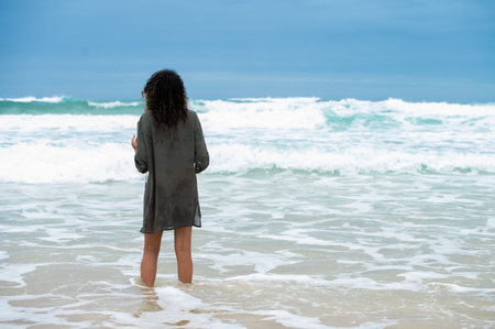 Woman seen standing in water as waves rush inの写真素材