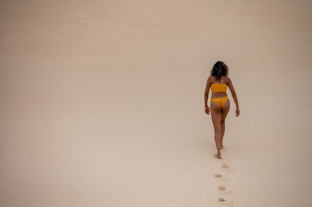 Rear view of woman walking along sandの写真素材