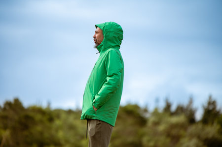 Side view of man with jacket standing in nature