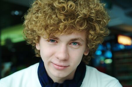 a smiling young man with curly hairの写真素材