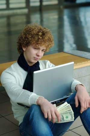 young man with a laptop computer and dollarsの写真素材