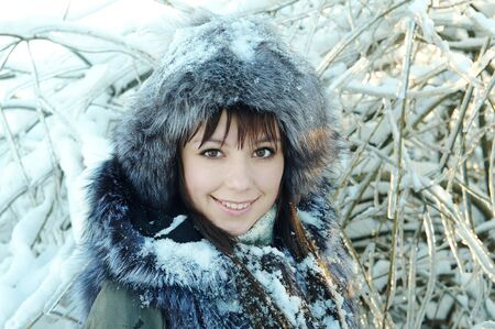 young woman winter day on the background of a snowy forestの写真素材