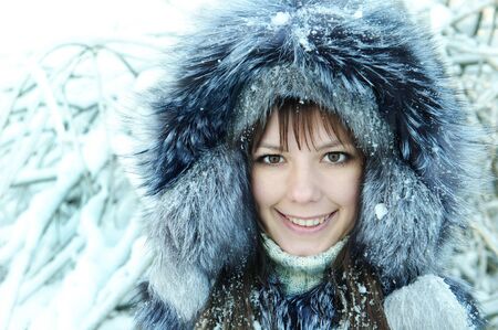 young woman winter day on the background of a snowy forestの写真素材