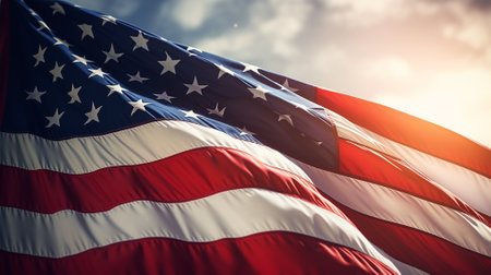 American flag waving in the wind against blue sky with sunflareの素材