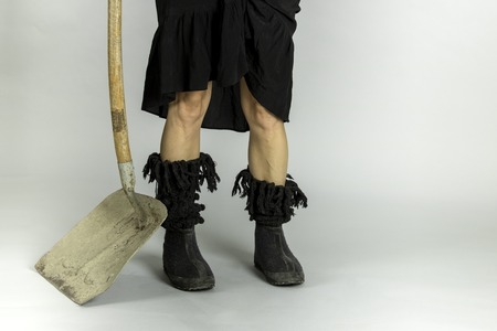 Woman in black shoes and shovel on gray backgroundの写真素材