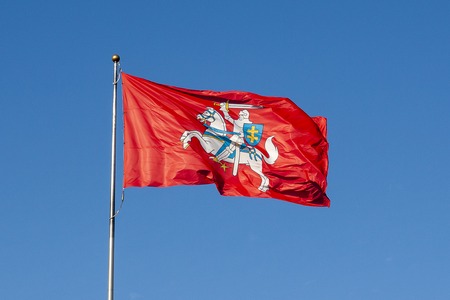 National bright red Lithuanian flag with a rider on a blue sky background