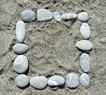 frame made of pebble stones lying on a sandの写真素材