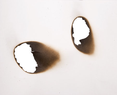 burnt holes in a paper の写真素材