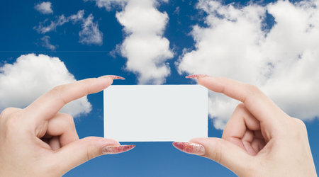 greeting card in a hand on a sky backgroundの写真素材