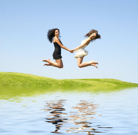 two happy jumping woman over skyの写真素材