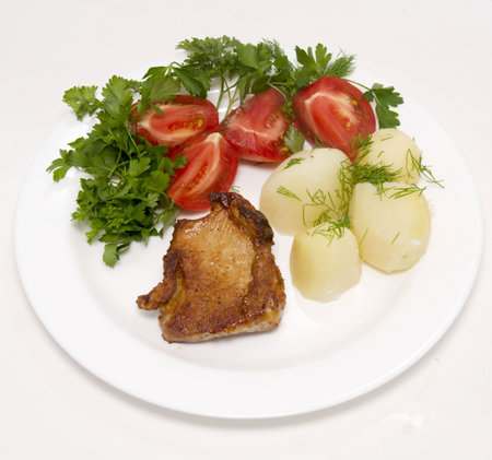 roasted meat with vegetables on white plateの写真素材