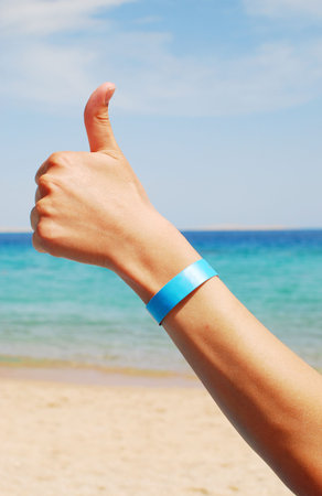 hand with all inclusive bracelet over sea backgroundの写真素材