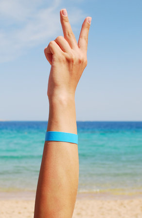 hand with all inclusive bracelet over sea backgroundの写真素材