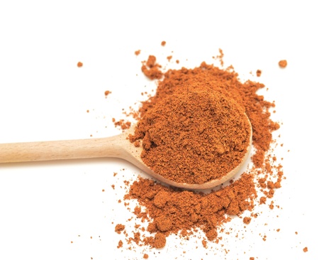 ground nutmeg in the wooden spoon isolated on whiteの写真素材