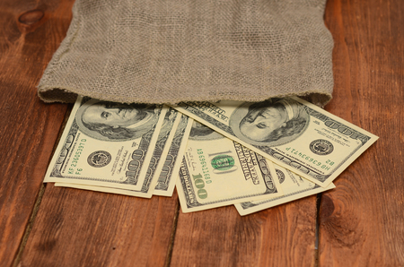 dollars with burlap sack on wooden backgroundの写真素材