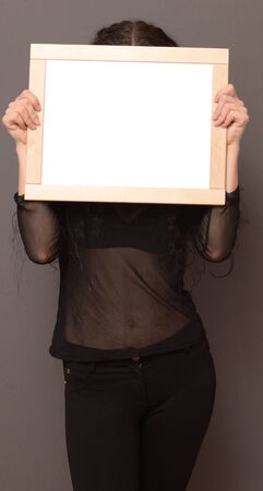 woman holding wooden frame in hand to hide her face の写真素材