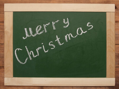 "Merry Christmas" handwritten with white chalk on a blackboardの写真素材