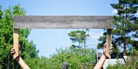 wooden sign board in a hands against sky