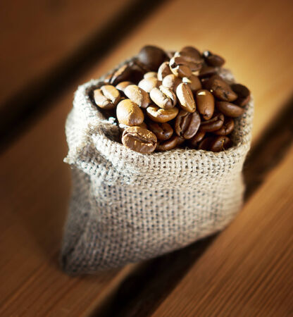coffee beans in a burlap sack on wooden backgroundの写真素材