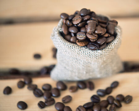 coffee beans in a burlap sack on wooden backgroundの写真素材