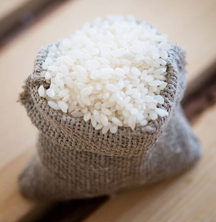 rice in burlap sack on wooden backgroundの写真素材