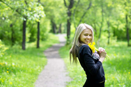 young beautiful woman with dandelions in the parkの写真素材