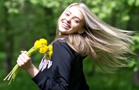 dancing happy smiling woman with dandelion flower against nature backgroundの写真素材