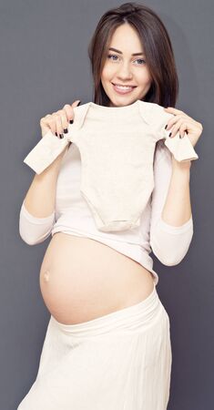 pregnant woman with her future baby's clothesの写真素材