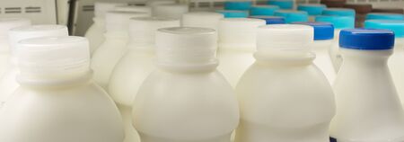 milk bottles on fridge shelf in supermarket storeの写真素材