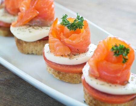 canapes with salmon and cheese on wooden tableの写真素材