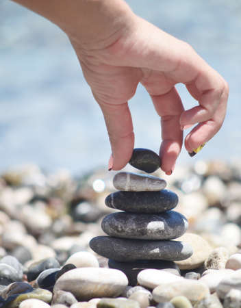 balancing pebble tower with female handの写真素材