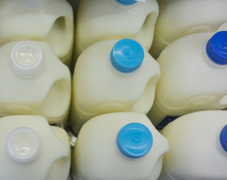milk bottles on fridge shelf in supermarket storeの写真素材
