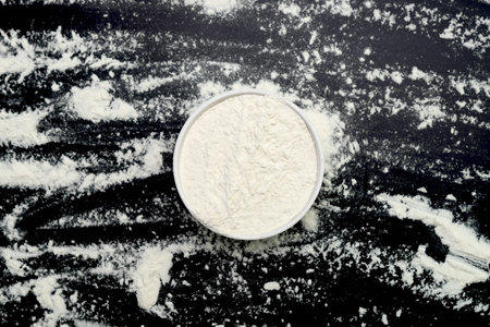 white flour in a white bowl on black background