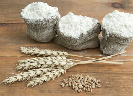 flour in sack with ears and grain on wooden table