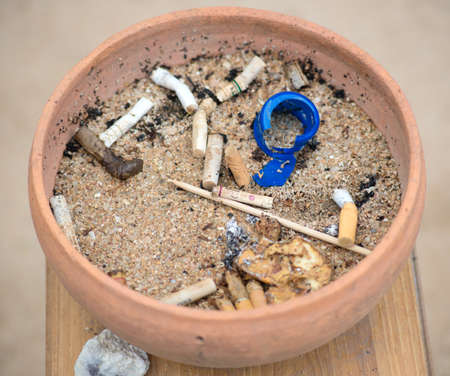 Clay ashtray with butts and sandの写真素材