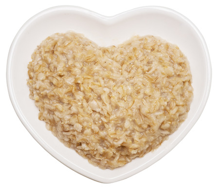 Oatmeal in heart shaped plate isolated on white backgroundの写真素材
