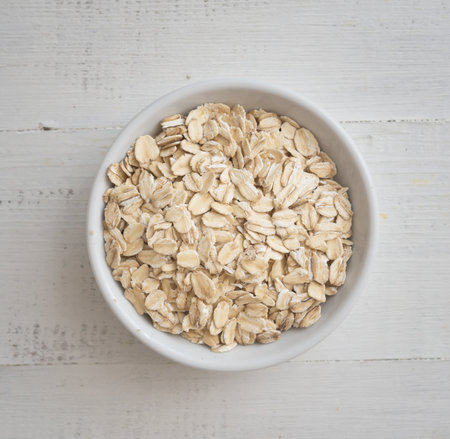 Uncooked oats in a bowl on a wooden background