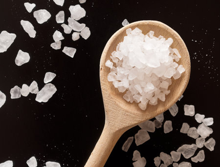 Sea salt with wooden spoon on a black background