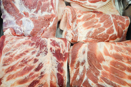 A close up of several pieces of meat, including pork chops and ribs. Concept of abundance and variety, as there are multiple types of meat on displayの写真素材