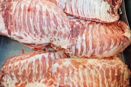 Rack of ribs is displayed in a metal tray. The ribs are white and red in color