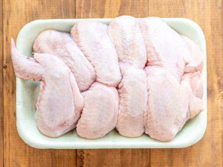 Chicken wings in tray on a wooden backgroundの写真素材