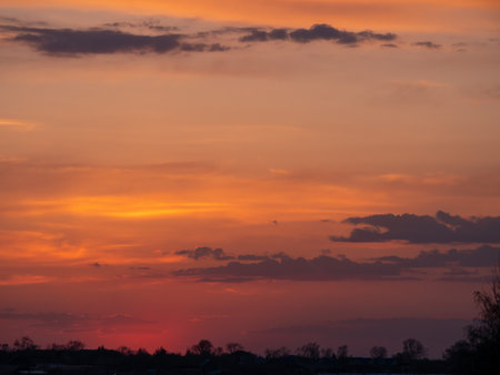 The sky is a beautiful orange color as the sun sets. The clouds are scattered throughout the sky, creating a peaceful and serene atmosphereの写真素材